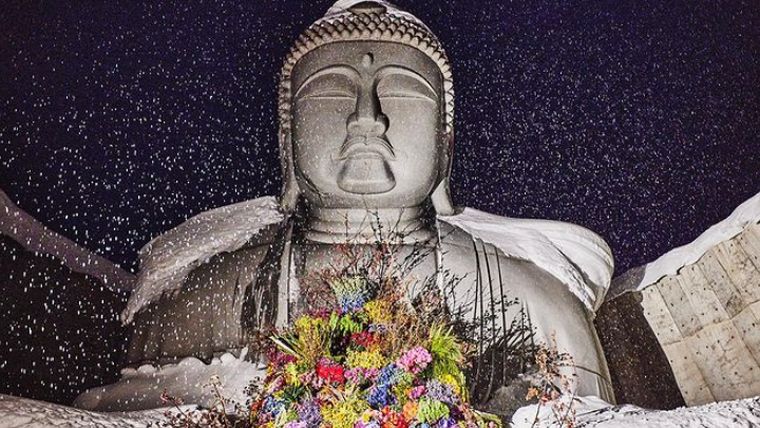 Ευχή για Ειρήνη με ένα μπουκέτο λουλουδιών στην αγκαλιά του Βούδα
